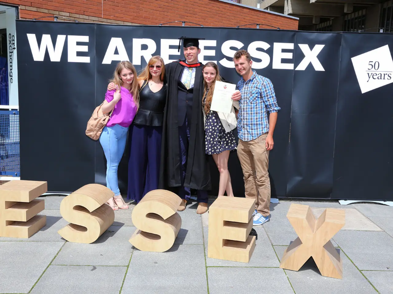 In this image we can see a group of people are standing, and smiling, and holding a certificate in...
