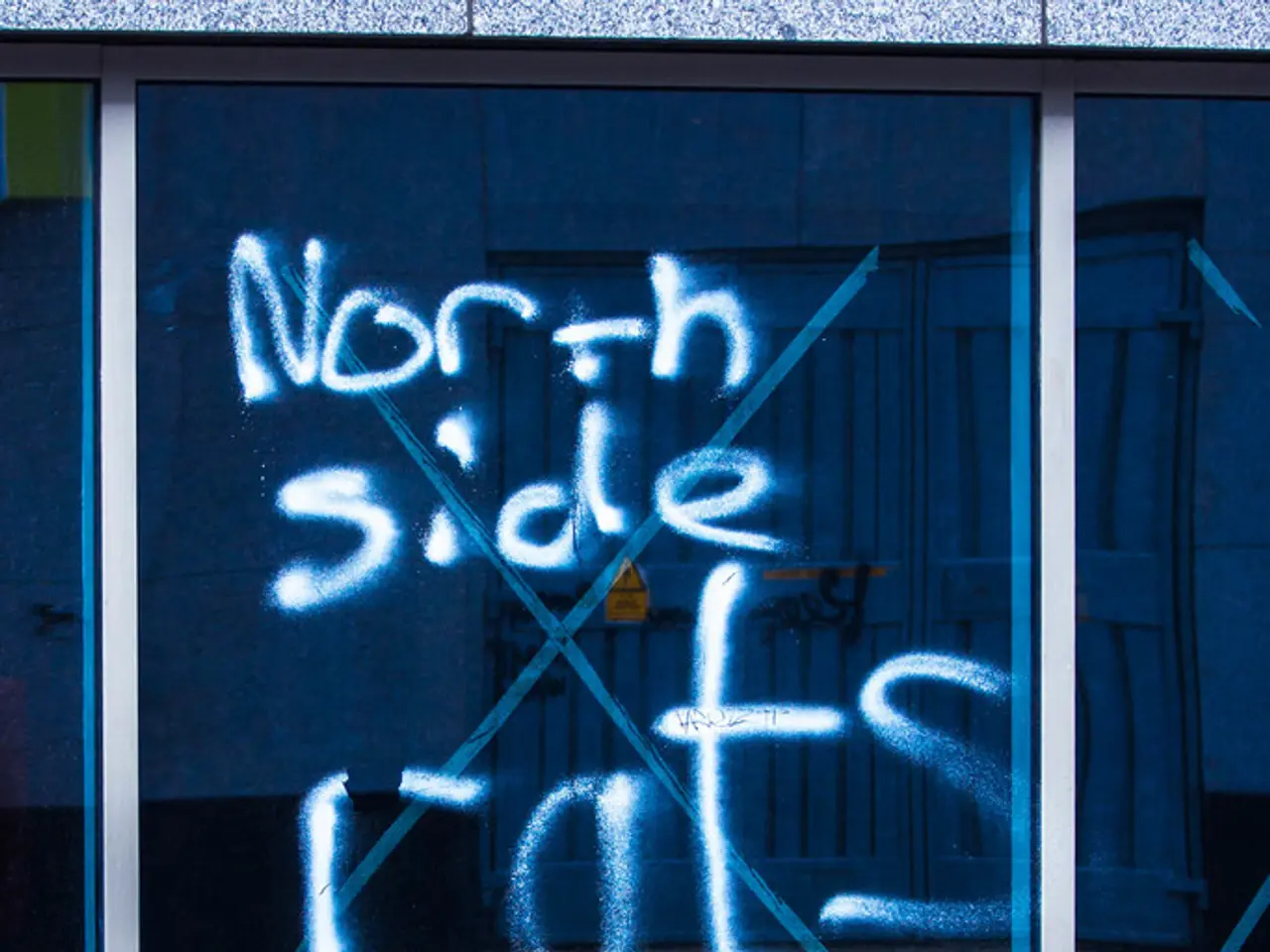 In this image we can see some text on the window and a barrier pole on the road.