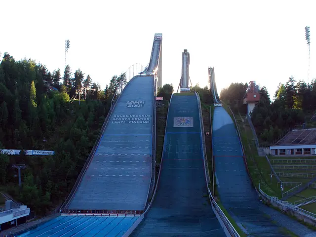 In this image we can see water rides. Bottom of the image fencing is there and the land is covered...