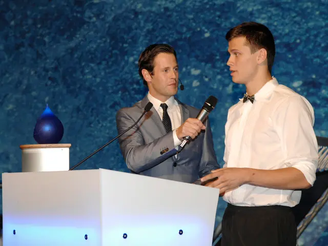 In this image two person standing. The person is holding a mic. There are standing in the front of...