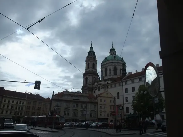 In this picture there are buildings in the center of the image and there is a pole and trees on the...