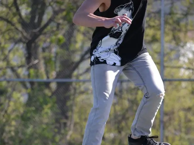 This picture is clicked outside. In the center we can see a person wearing t-shirt and skating on...