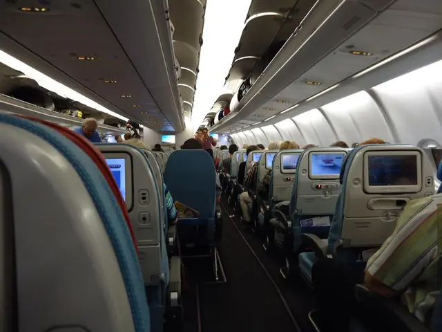 Here we can see an inside view of an airplane, we can see chairs here, there are some people...