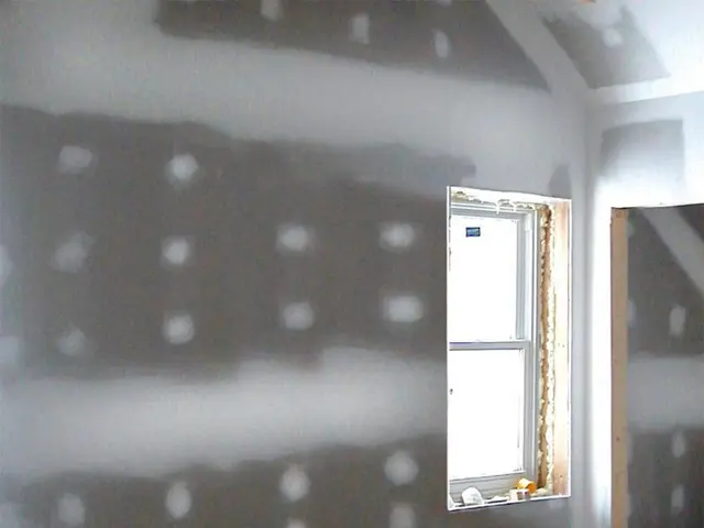 In this image there is a glass window on the wall, beside the window there is an entrance to...