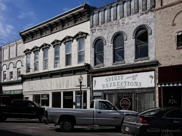 This picture shows building and we see a car and couple of mini trucks parked and we see a pole...