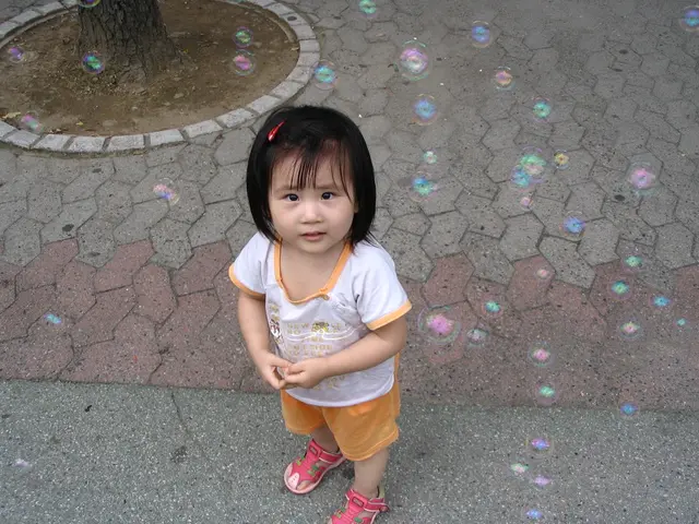 In this image there is a child standing on the ground, the child is truncated towards the bottom of...