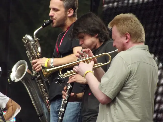 In the image there are three men standing and playing different music instruments. On the left side...
